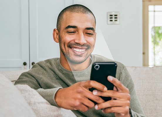man smiling at smart phone device with screen shining on face