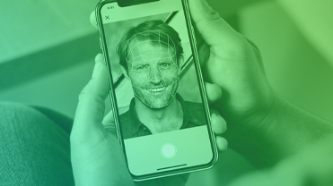 person holding phone displaying a man with biometric lines on face